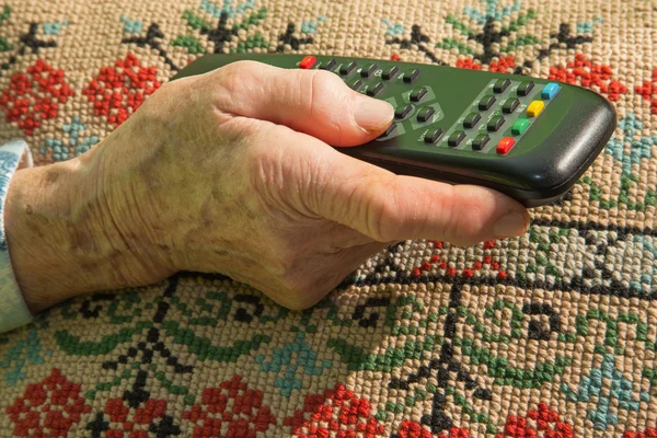 Hand van oude vrouw met Tv stuurprogramma — Stockfoto