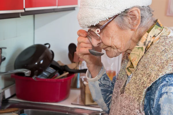 Die alte Frau bei der Verkostung auf dem Essen — Stockfoto