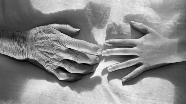 Hands of grandmother and grandchild in the bed — Stock Photo, Image