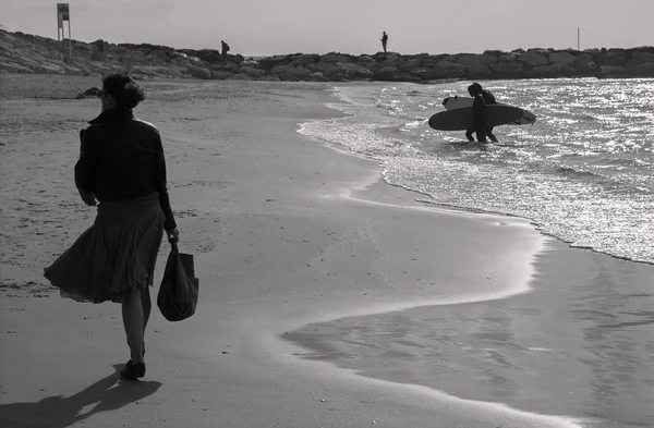 TEL AVIV, ISRAELE - 2 MARZO 2015: La silhouette della donna camminata e dei surfisti sulla spiaggia di Tel Aviv . — Foto Stock