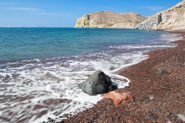 Santorini - adanın güney kısmından kırmızı sahilde dalgalar.