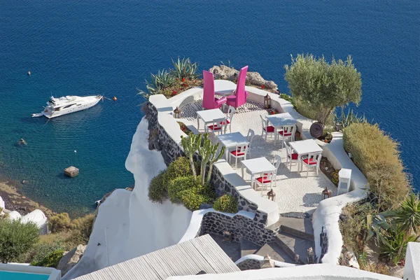 Santorini - O restaurante voltado para o jantar romântico de casamento em Oia (Ia) e o iate sob falésias no fundo. — Fotografia de Stock