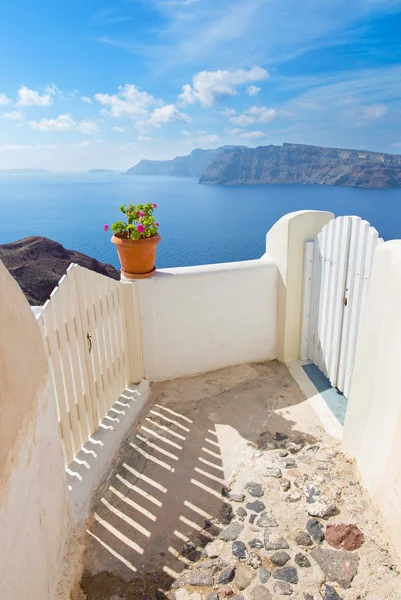 Santorini - malá brána do domu v Oia a Therasia ostrov v pozadí. — Stock fotografie