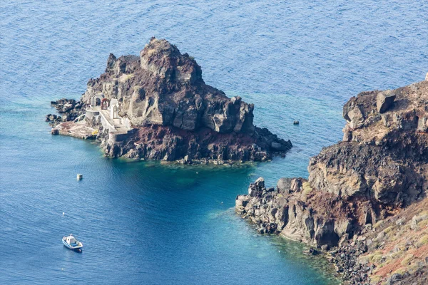 Santorini - Piccola isola sotto la costa di Oia con piccola cappella. — Foto Stock