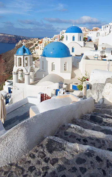 Santorini - Utseendet på typiskt blå kyrka kupoler i Oia över caldera och Therasia ön i bakgrunden. — Stockfoto