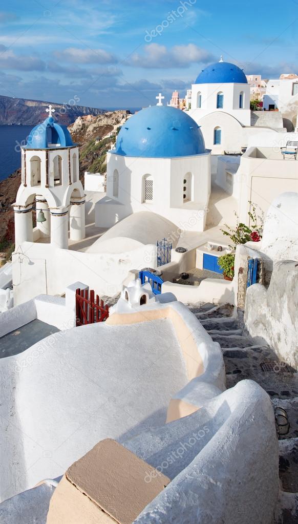 Santorini - The look to typically blue church cupolas in Oia over the caldera and the Therasia island in the background.