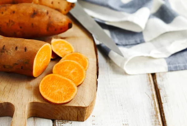 Patatas dulces crudas sobre tabla de cocción de madera —  Fotos de Stock