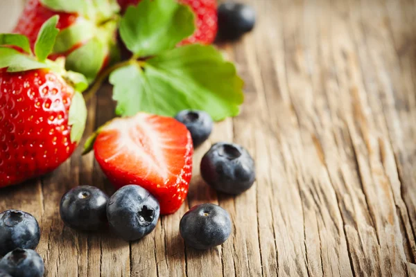 Fragole fresche e mirtilli su fondo di legno — Foto Stock