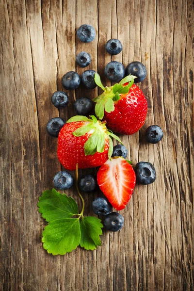 Fragole fresche e mirtilli su fondo di legno — Foto Stock