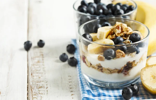 Joghurtot, házi granola, banán és fekete áfonya. — Stock Fotó