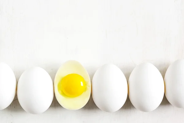 Oeufs blancs alignés sur un fond en bois blanc — Photo