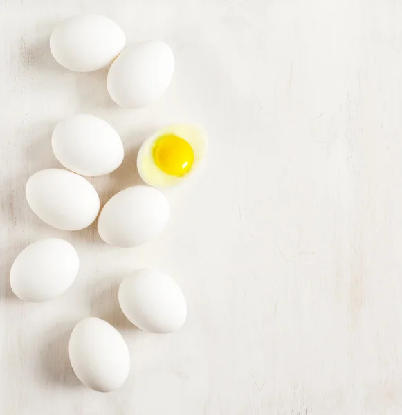 Oeufs blancs alignés sur un fond en bois blanc — Photo