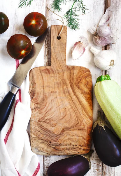 Verse groenten rond houten snijplank — Stockfoto