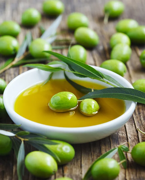 Olive oil and fresh green olives with leaves — Stock Photo, Image