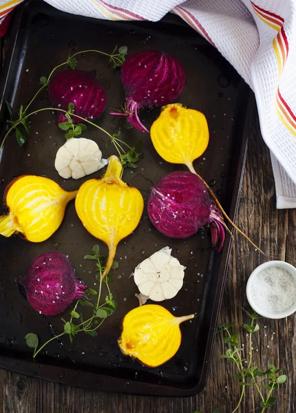 Preparing raw beetroots and garlic for roasting on a baking tray — Stock Photo, Image