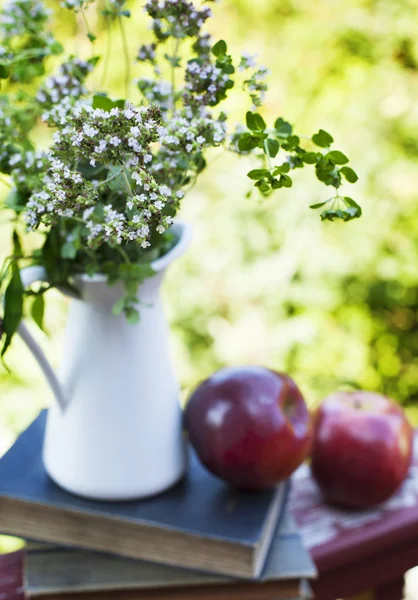 Summer wild flowers in glass vase, old books and apples. — Stock Photo, Image