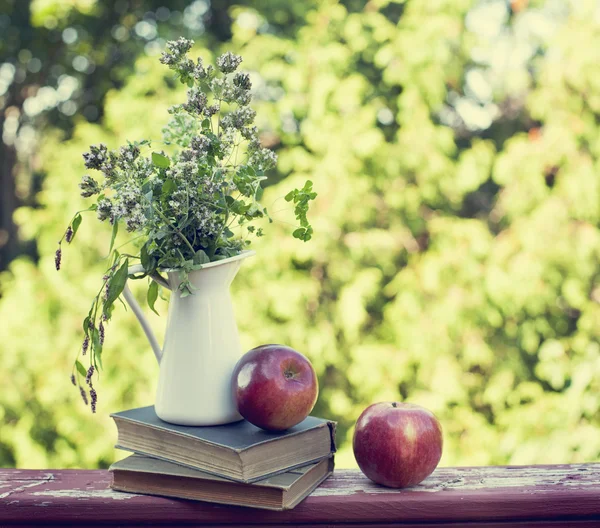 Zomer wilde bloemen in glazen vaas, oude boeken en appels. — Stockfoto