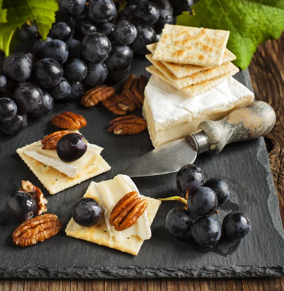 Delicious cheese crackers appetizer with grapes and pecans — Stock Photo, Image