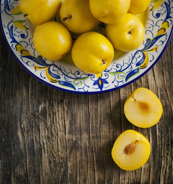 Fresh yellow plums in a plate on wooden background — Stock Photo, Image