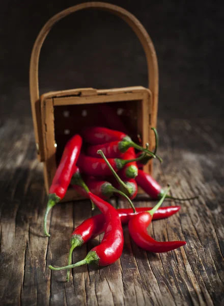 Rote Chilischoten im Korb auf dem hölzernen Hintergrund. — Stockfoto