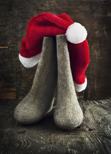 Weihnachtsmann-Mütze und Filzstiefel auf Holzgrund, — Stockfoto