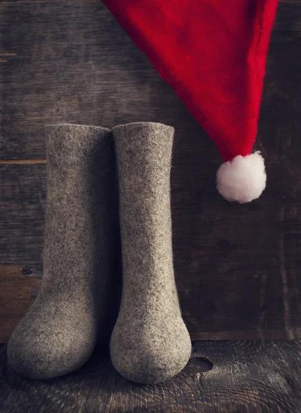Sombrero de Navidad de Papá Noel y botas de fieltro sobre fondo de madera , —  Fotos de Stock