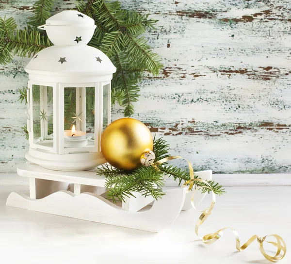 Kerstkaart met kaars lantern en slee op houten backgrpu — Stockfoto