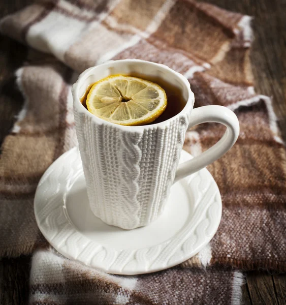 Tazza di tè caldo con limone e sciarpa sul tavolo di legno — Foto Stock