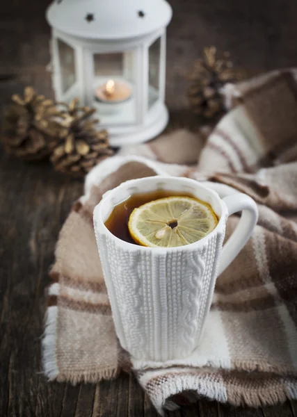 Taza de té caliente con limón y bufanda en la mesa de madera — Foto de Stock