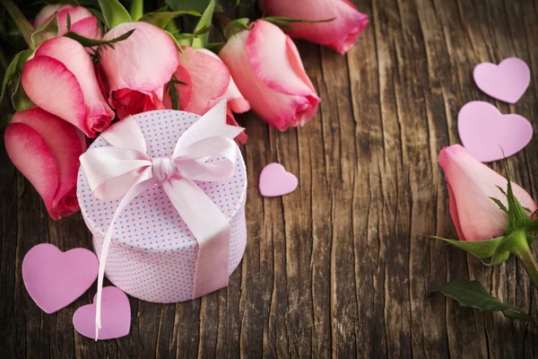 Bouquet van roze rozen en de doos van de gift op houten achtergrond — Stockfoto