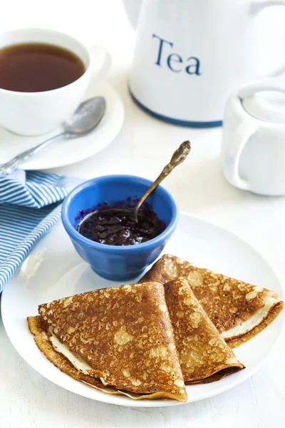 Crepes caseros doblados en triángulos con mermelada de grosella negra y taza de té —  Fotos de Stock