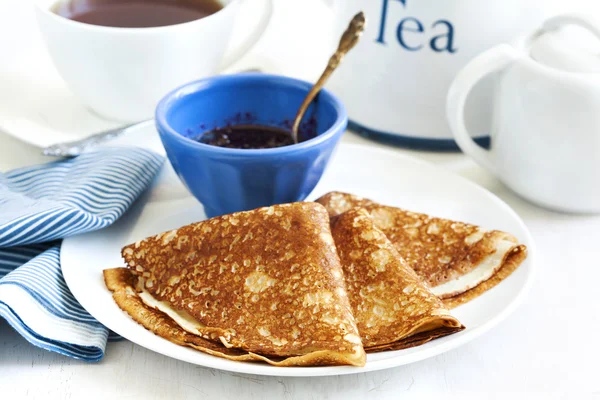 Homemade crepes folded in triangles with black currant jam and cup of tea — Stock Photo, Image