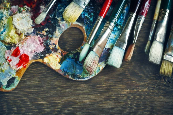 Artist paint brushes and palette on wooden background — Stock Photo, Image