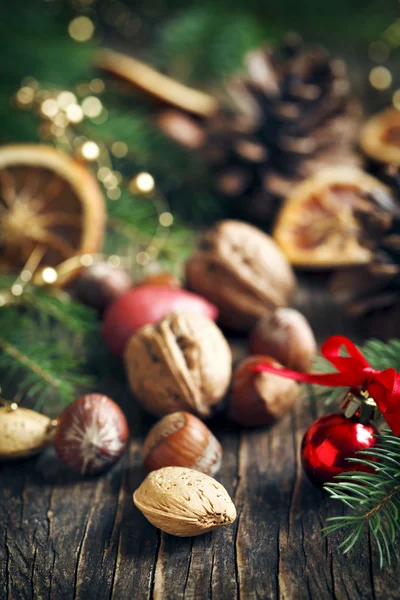 Diferentes nueces con decoraciones navideñas sobre fondo de madera —  Fotos de Stock