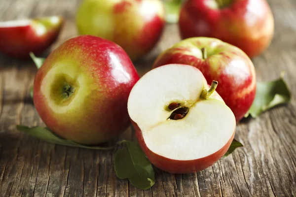 Свежие органические яблоки с листьями на деревянном фоне — стоковое фото