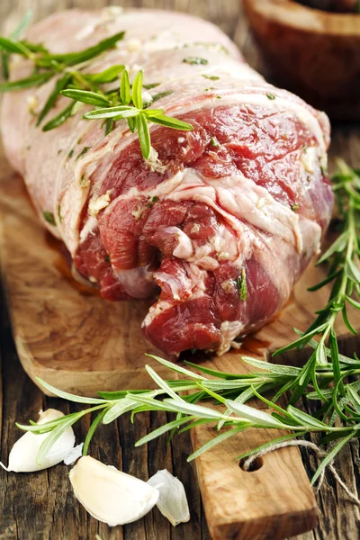 Raw boneless lamb leg with garlic and rosemary on wooden backgro — Stock Photo, Image