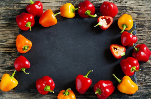 Mini Bell Peppers on wooden background with black board — Stock Photo, Image