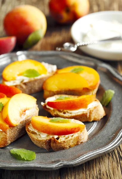 Crostini with cream cheese and fresh peaches. — Stock Photo, Image