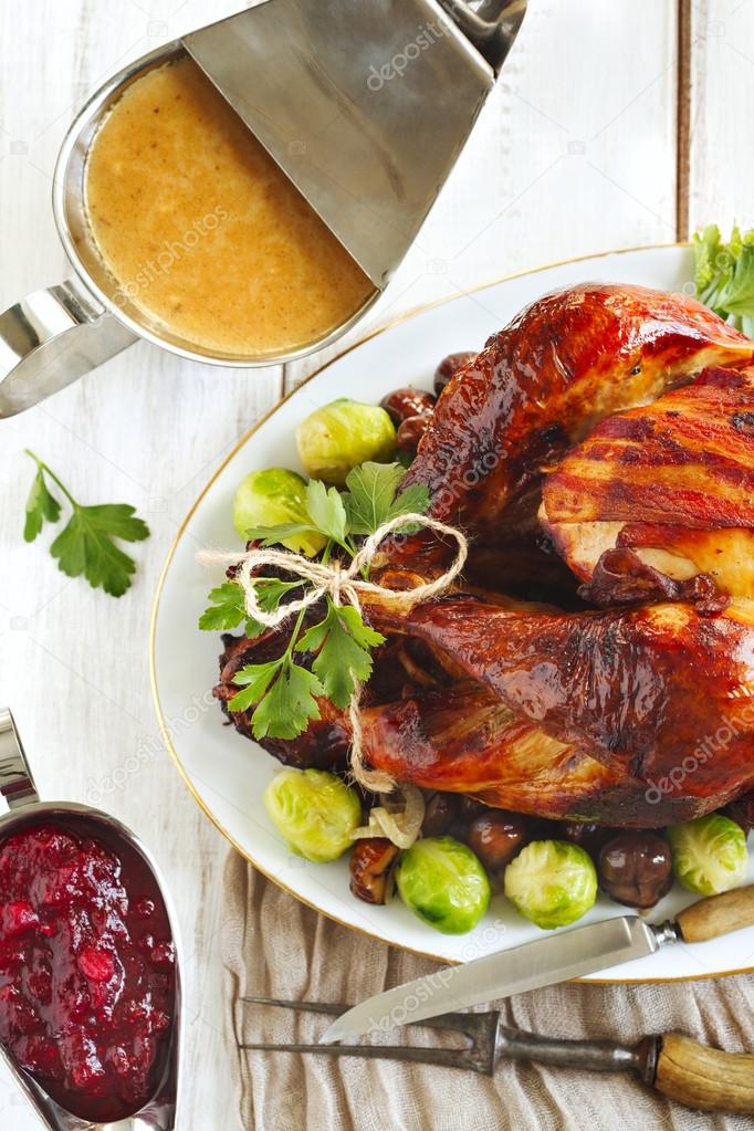 Roasted turkey with bacon and garnished with chestnuts and brussels sprouts.