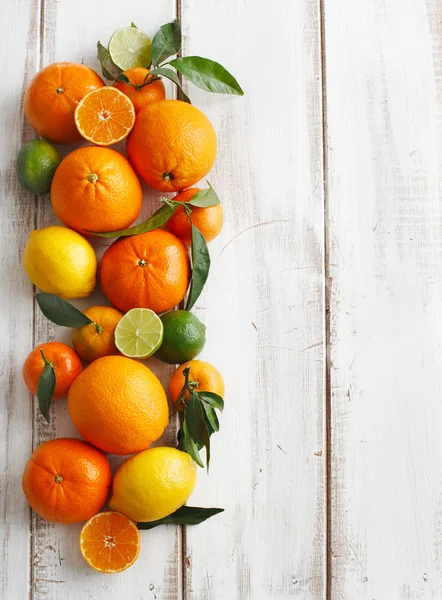 Färska citrusfrukter med blad på trä bakgrund — Stockfoto