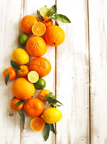 Färska citrusfrukter med blad på trä bakgrund — Stockfoto