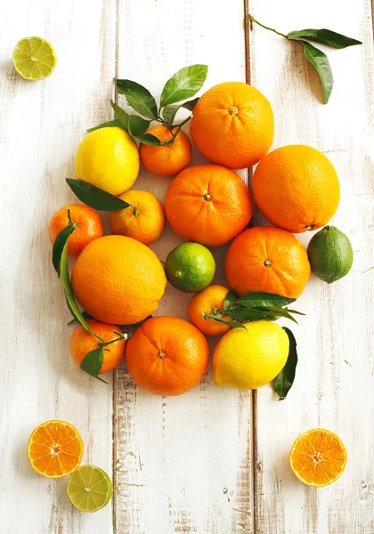 Färska citrusfrukter med blad på trä bakgrund — Stockfoto