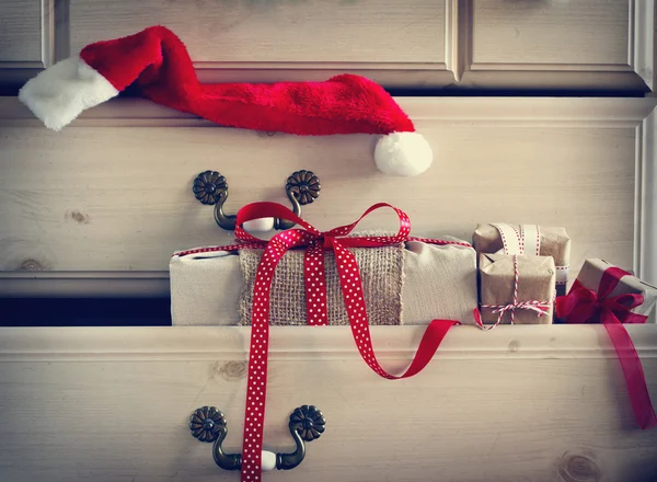 Christmas gift and Santa Claus hat in dresser drawer — Stock Photo, Image