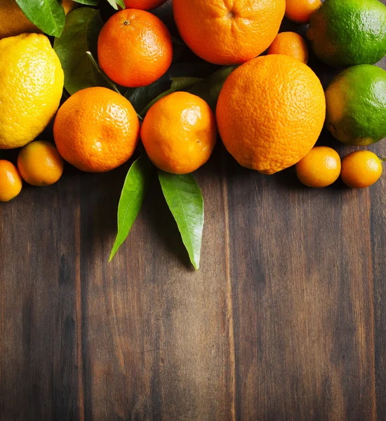 Čerstvé citrusové plody s listy na dřevěné pozadí — Stock fotografie