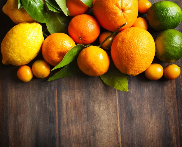 Verse citrusvruchten met bladeren op houten achtergrond — Stockfoto