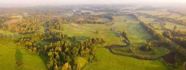 Świeże zielone krajobrazy z lasami, łąkami i rzeką oświetlone wschodzącym słońcem — Zdjęcie stockowe