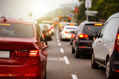 Gün batımında yolda bekleyen uzun araba kuyruğu olan bir şehirde trafik sıkışık.