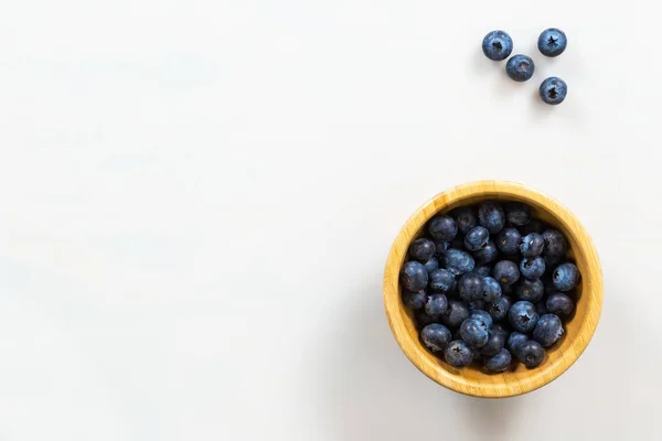 Wooden bowl of blueberries on side of white background — Stock Photo, Image
