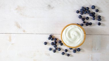 Fotokopi alanı olan bir masada olgun mavi meyveli beyaz yoğurt.
