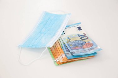 Avro banknotları beyaz masanın üzerinde mavi cerrahi maskenin altında yatıyor.